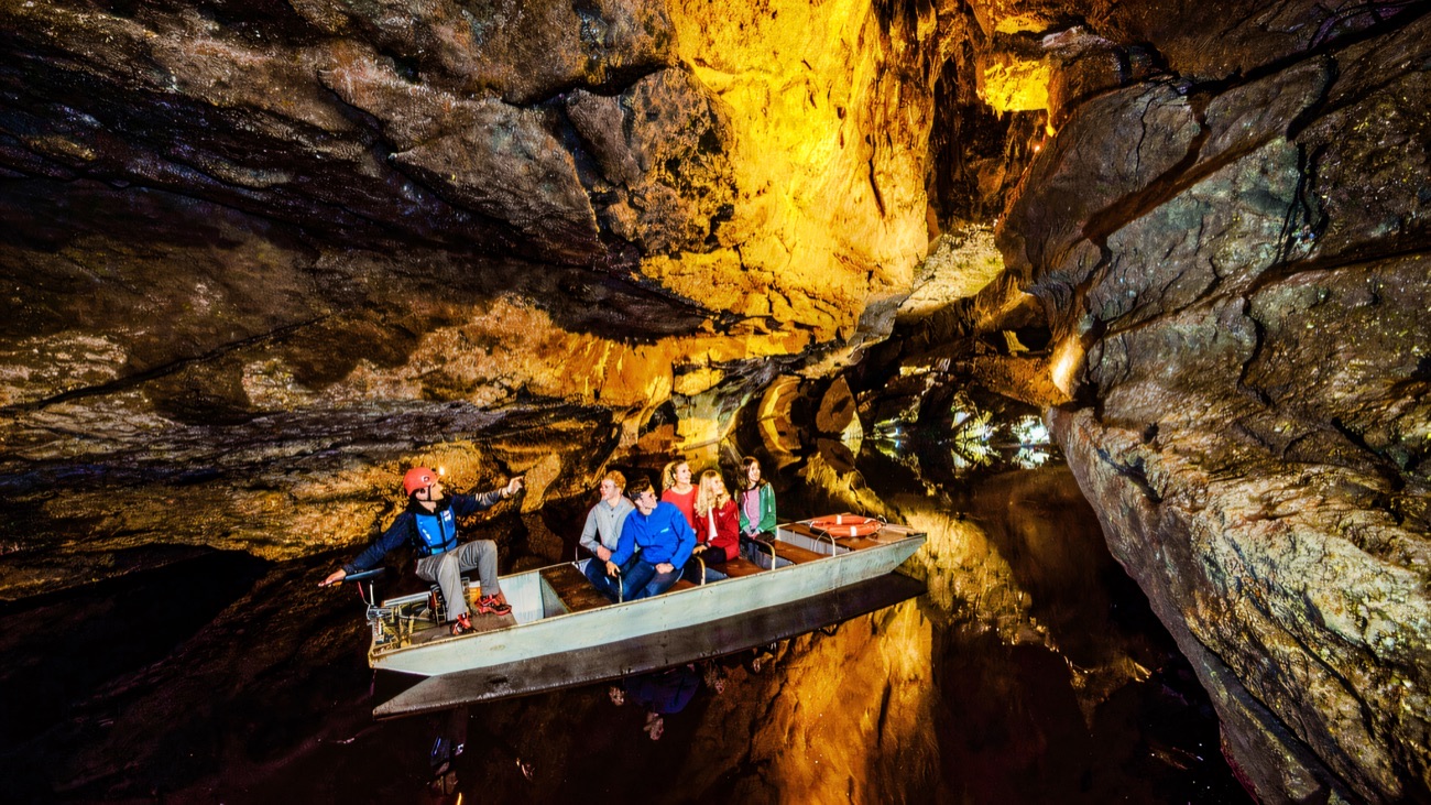 A guided tour boat gliding along the underground river between rock walls at Marble Arch Caves
