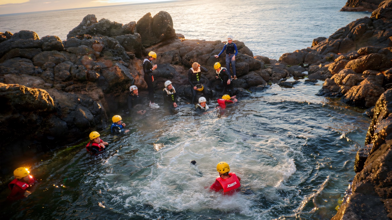 Coasteering plunge into a rock pool, helmets on and grins guaranteed