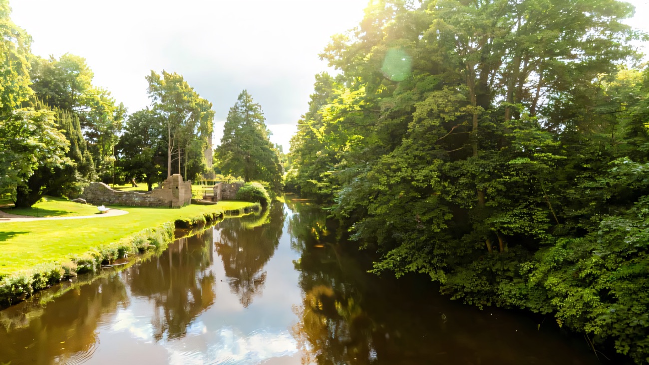 The Six Mile Water flowing calmly through the wooded grounds past the garden lawns