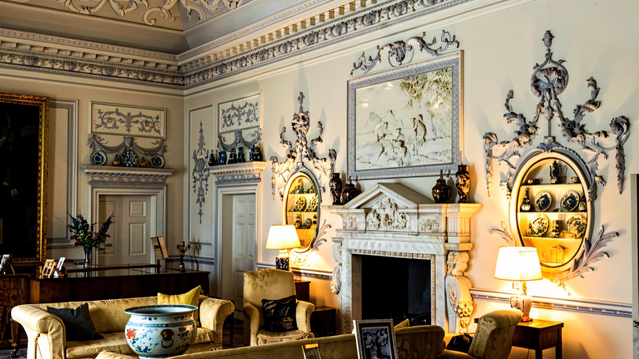 The pale plasterwork drawing room at Ardress House with an ornate decorated ceiling, wall panels and a fireplace