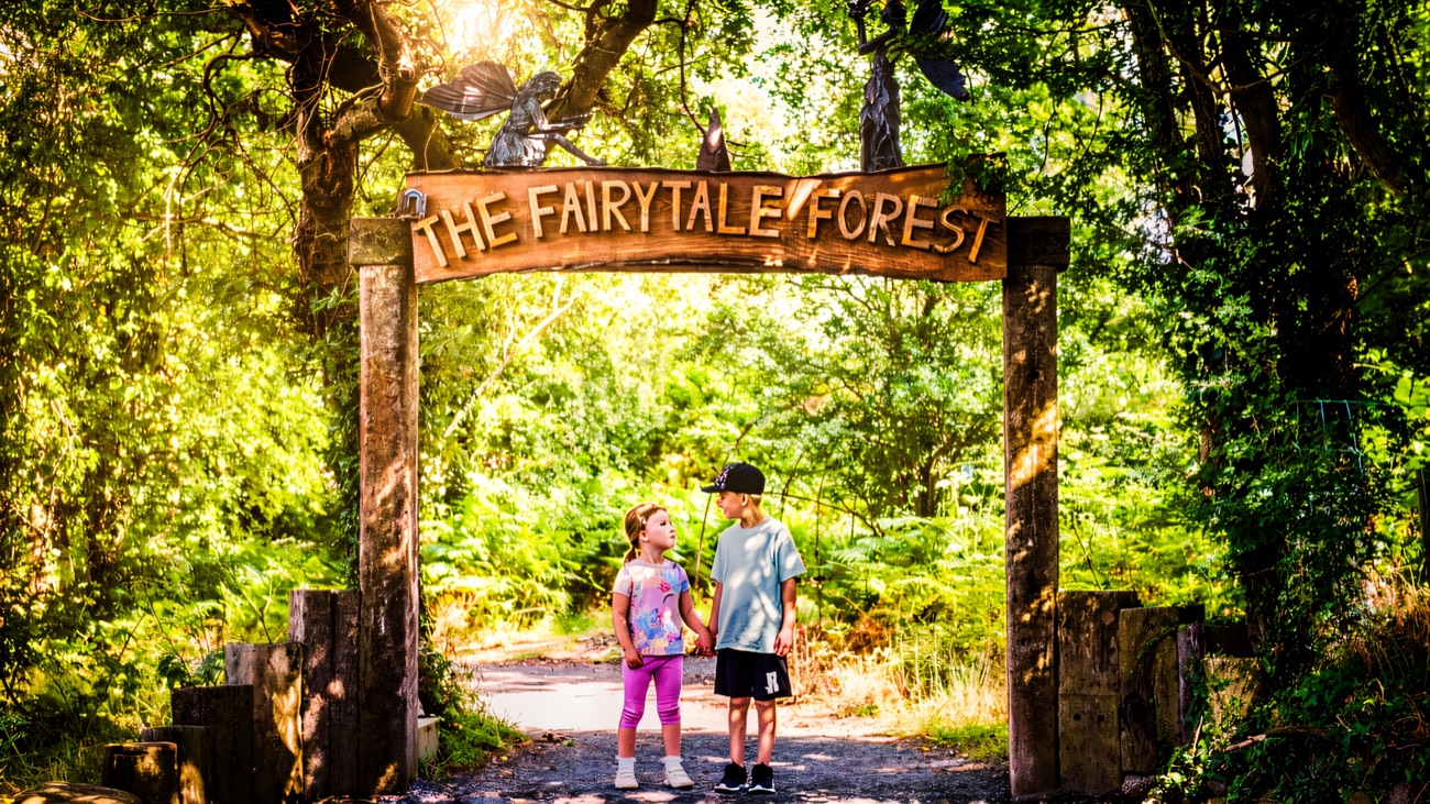 The carved wooden Fairytale Forest entrance arch over a woodland path