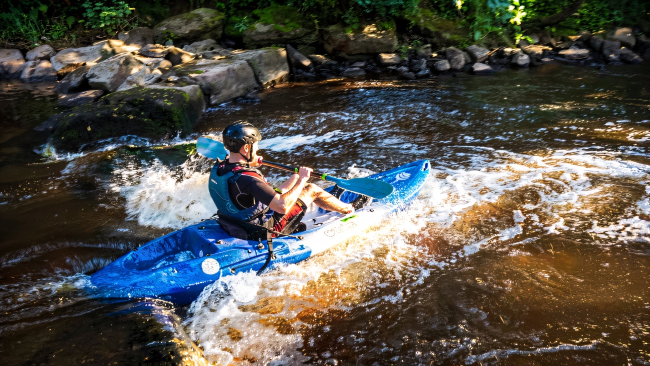 Running the weir in a whitewater kayak, spray flying