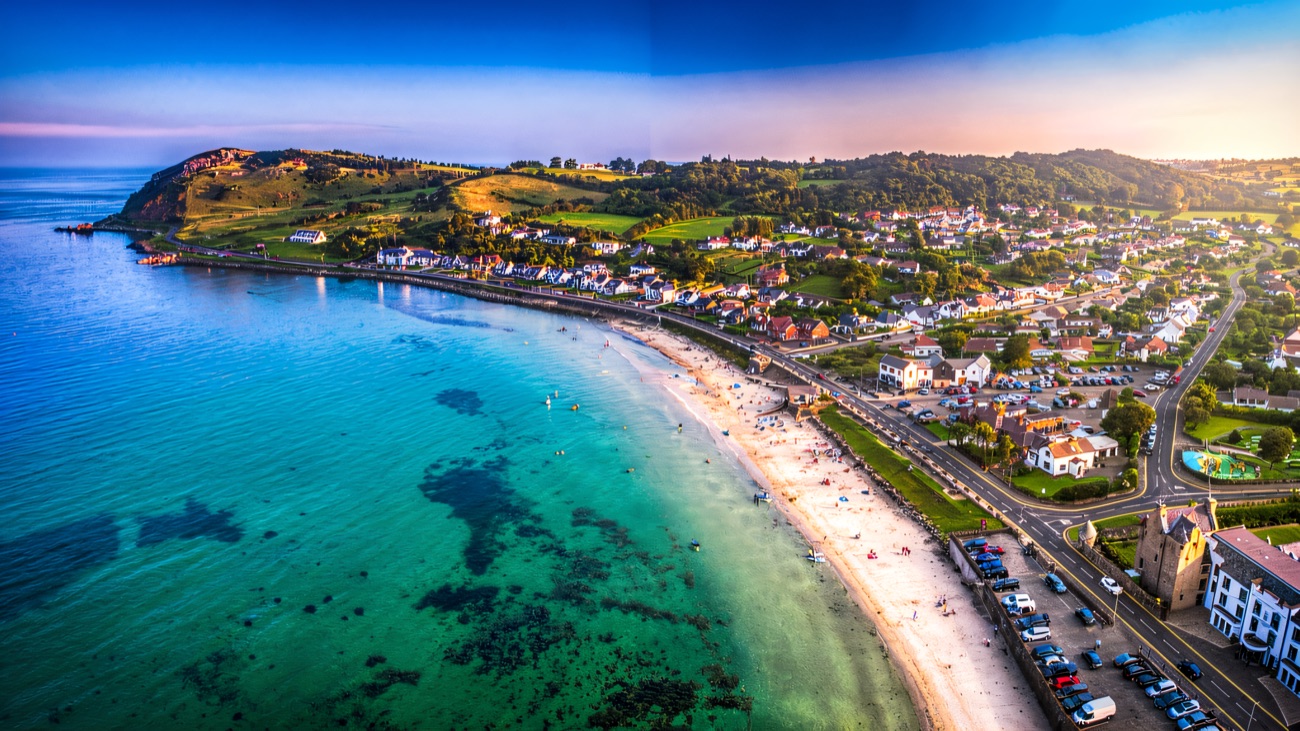 Ballygally bay from above, clear shallow water curving along the sand and the coast road