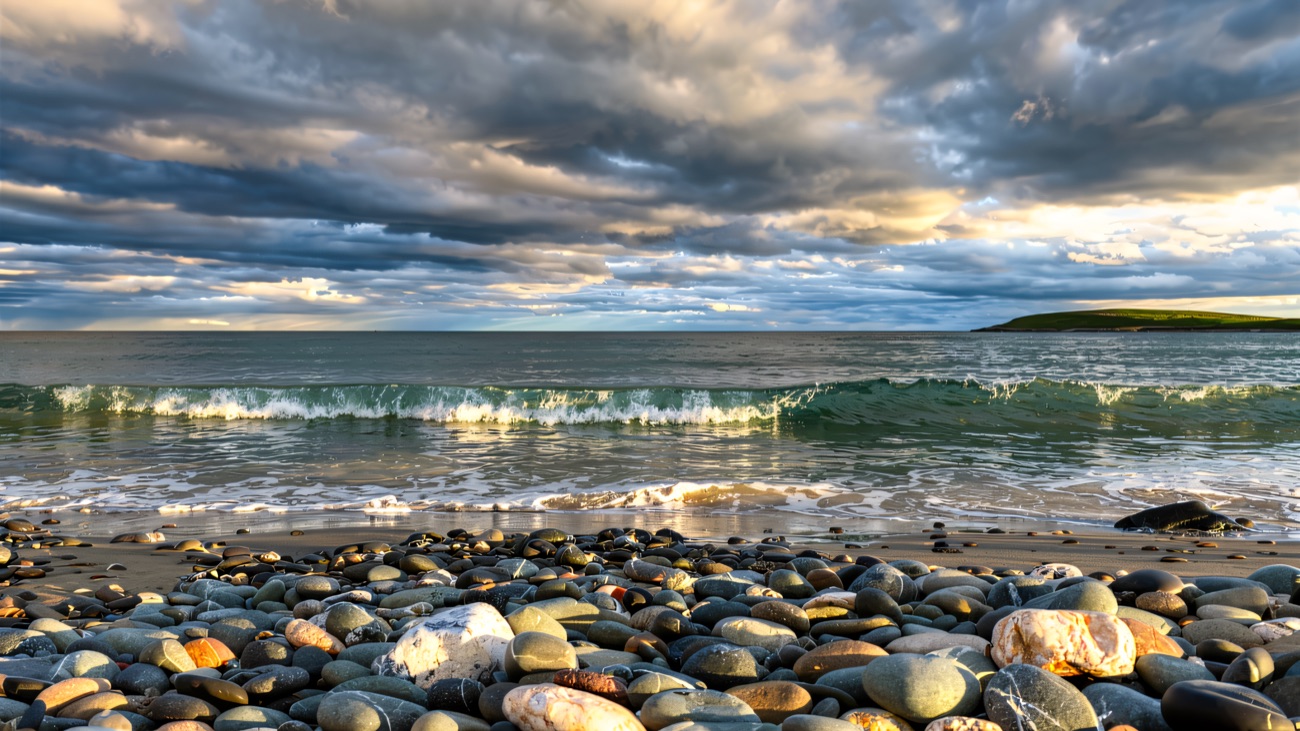 Small waves breaking onto the pebble bank, big cloud sky above the bay