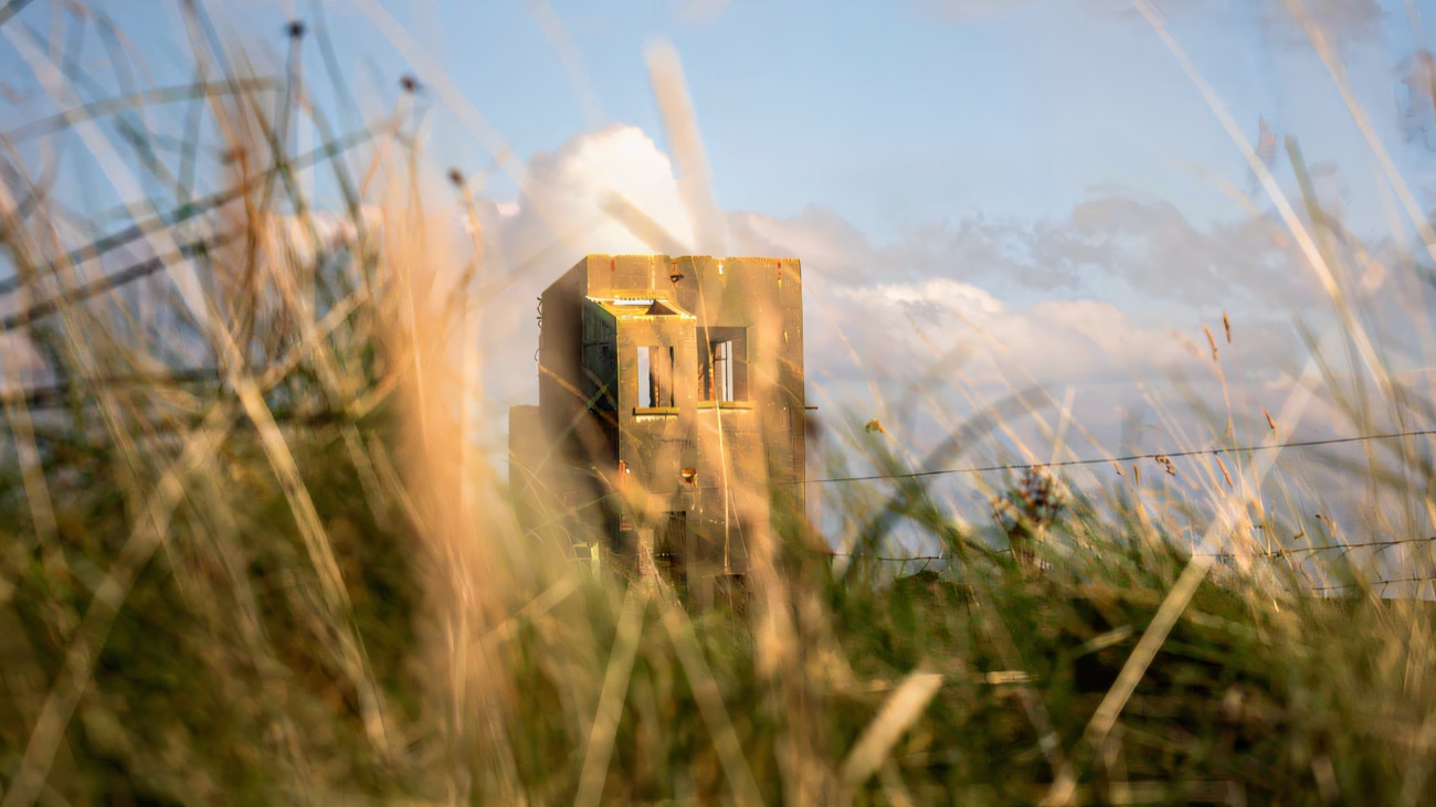 An old concrete lookout post half-hidden in the shore grass