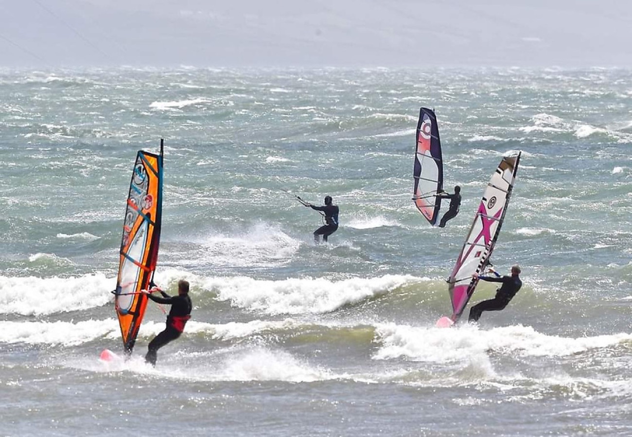 Windsurfers out on the waves off the north coast, sails bright against the sea