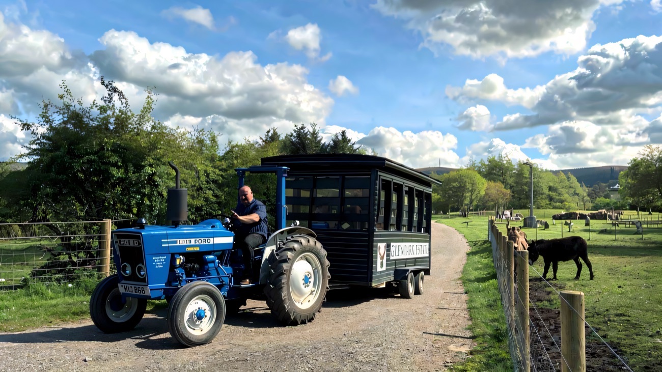 The Glenpark Estate tractor and trailer tour passing a donkey at the fence with the Sperrins behind