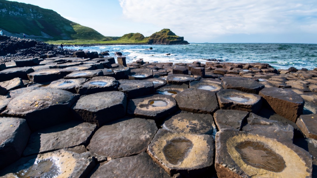 Flat-topped basalt columns of the Giant's Causeway stepping into a blue sea