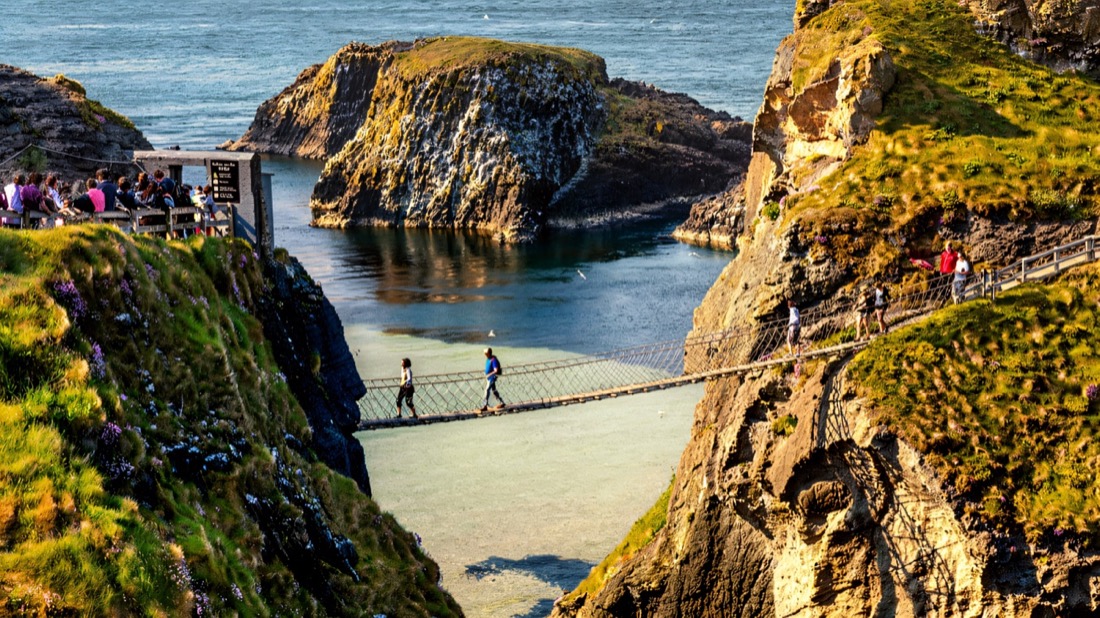 Walkers crossing the Carrick-a-Rede rope bridge high above blue-green water
