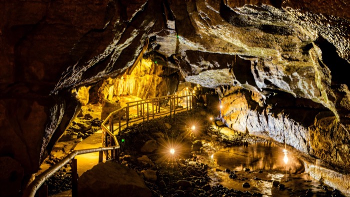 A lit walkway winding through a floodlit chamber in Marble Arch Caves