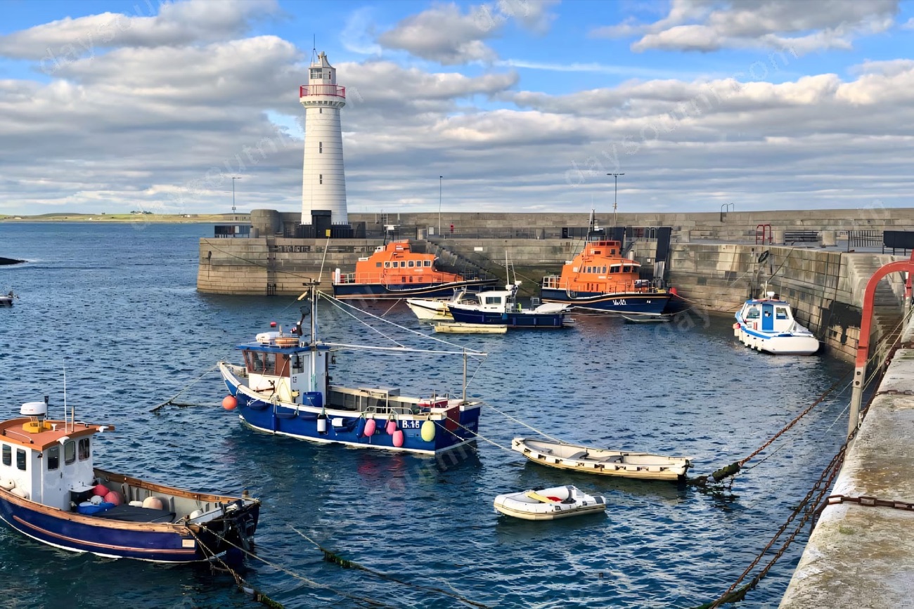 Donaghadee harbour with the white lighthouse, fishing boats and lifeboats — the swimmers' slipway is on this seafront