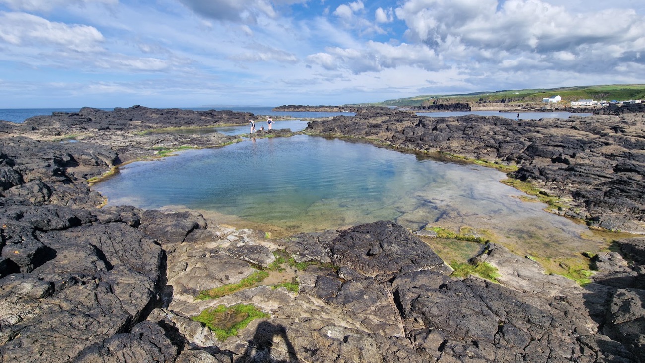 The deep natural rock pool at Dunseverick with swimmers