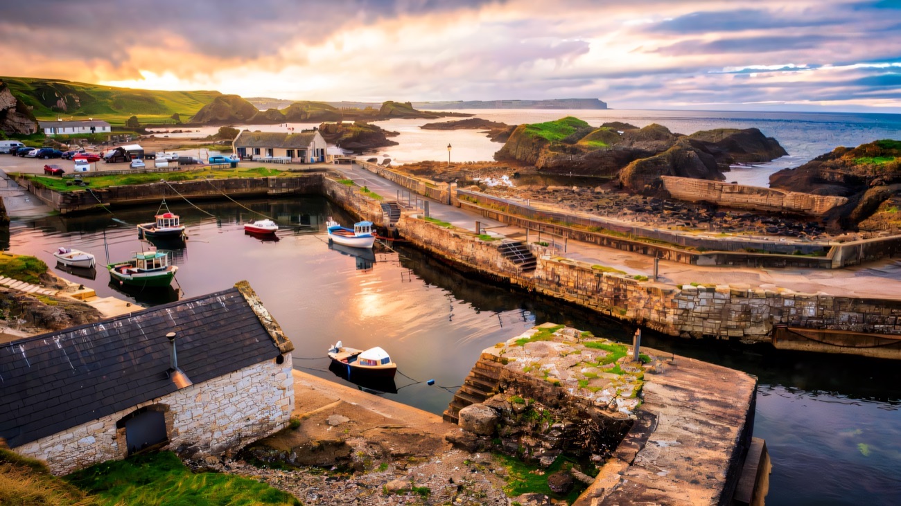 Ballintoy Harbour at sunset with boats moored and rocky foreshore all around