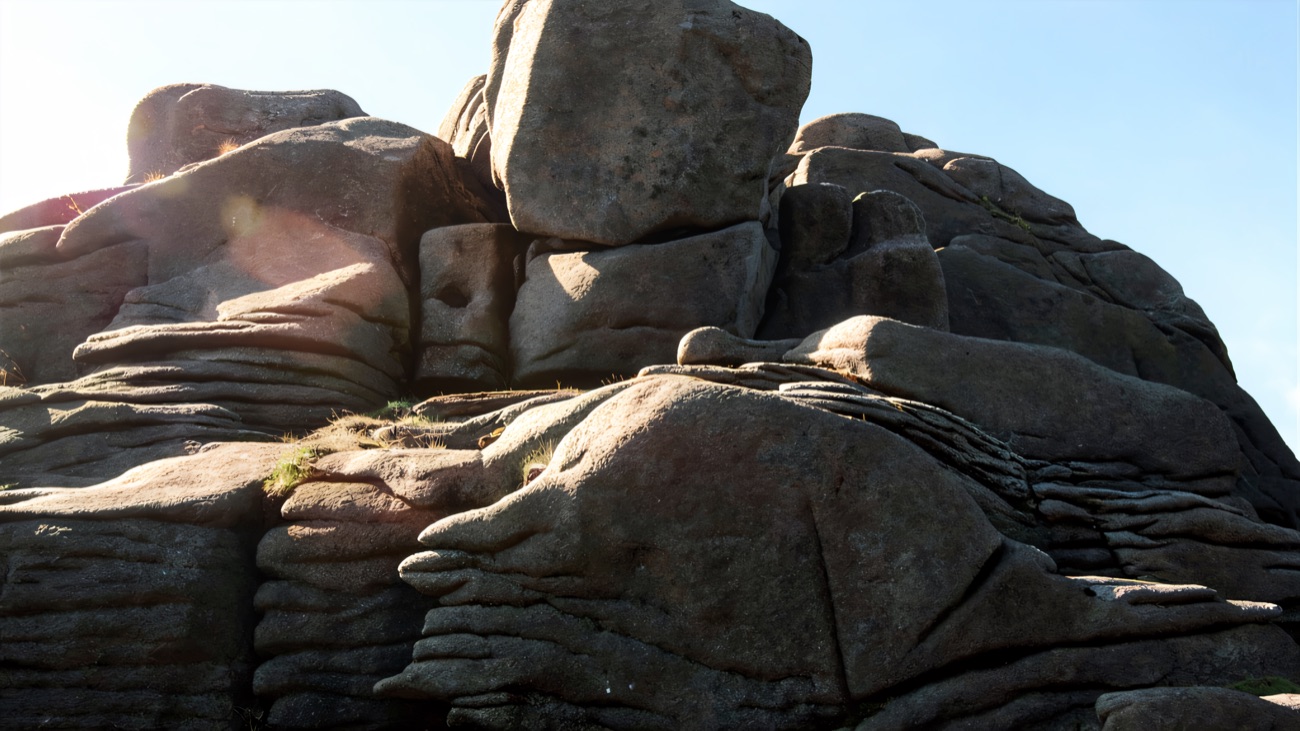 Close view of the stacked granite slabs and boulders of the tor against a blue sky.