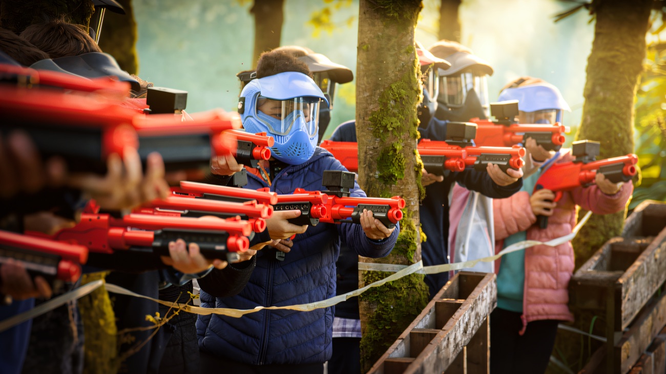 Masked players lined up with laser tag markers among the mossy woodland trees