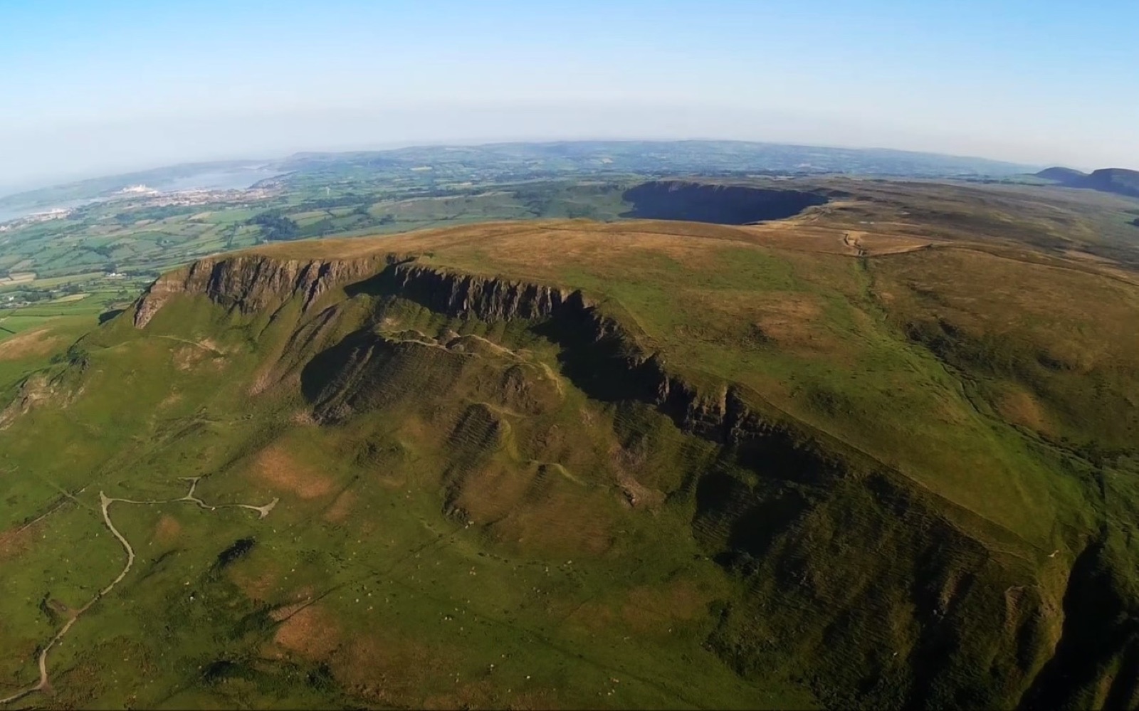 The Knock Dhu escarpment plateau above Cairncastle, green hills falling to the Antrim coast beyond