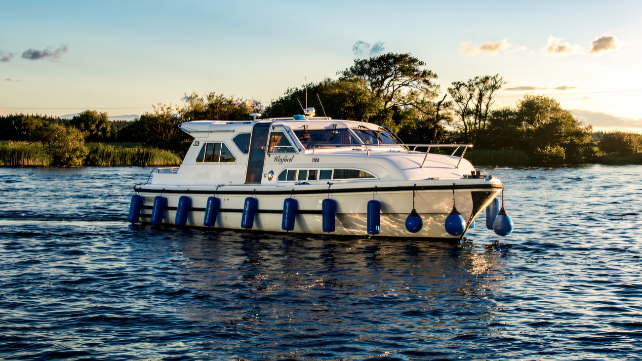 The cruiser sits on calm golden-hour water, its lines mirrored below