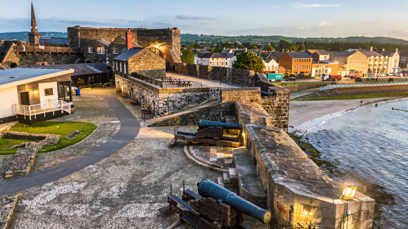 Cannons lined along the ramparts of Carrickfergus Castle looking out over the harbour and the town