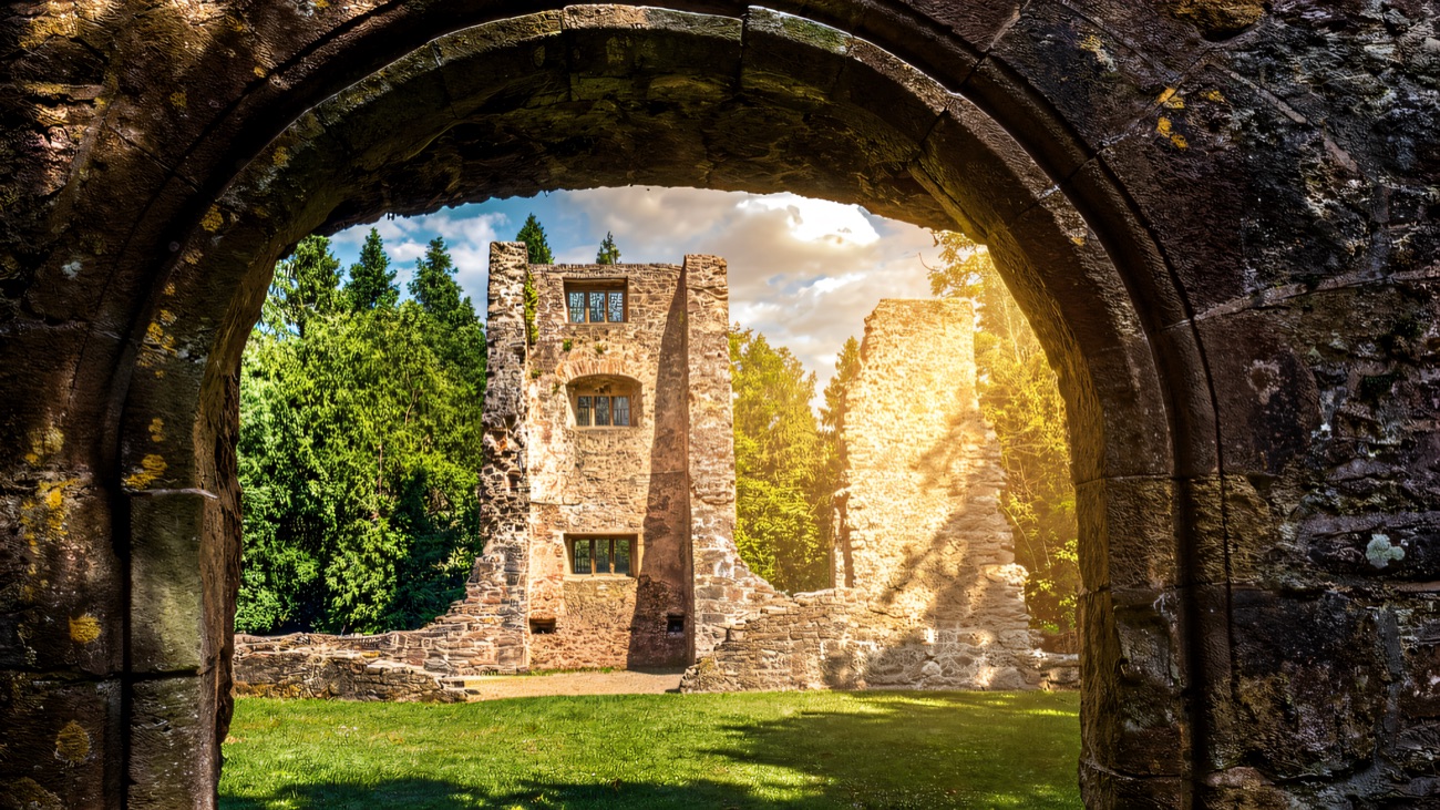 A stone archway framing the ruins of the old manor