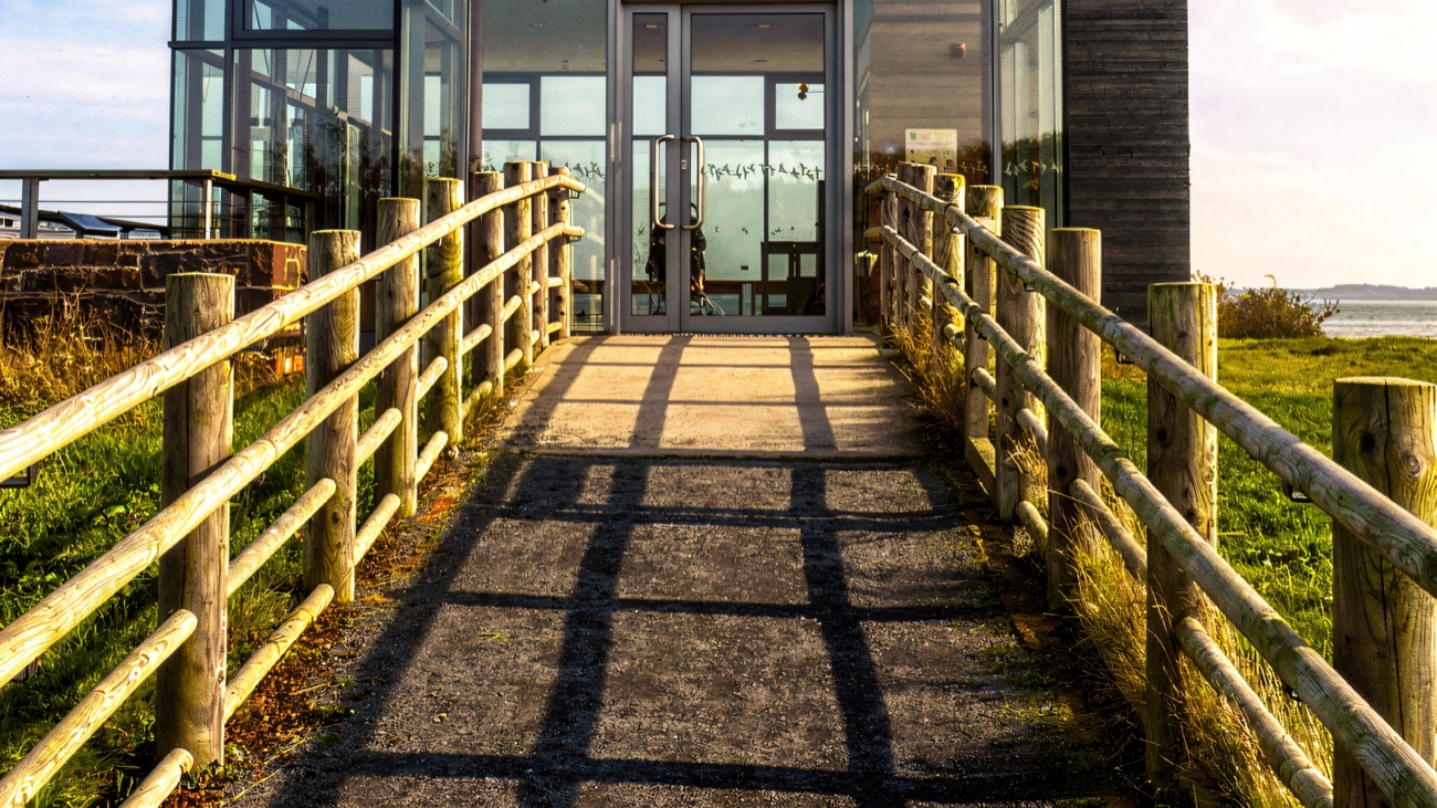 The glass Limekiln Observatory hide standing at the water's edge on the reserve