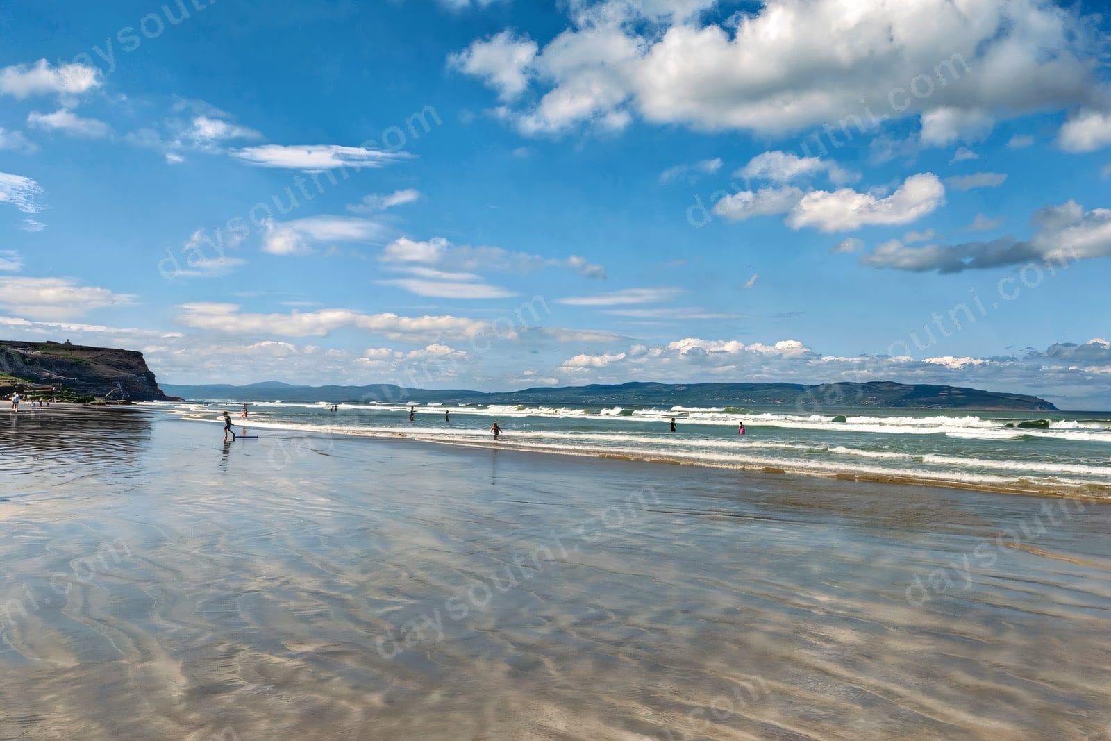 The wide sandy beach at Castlerock with the Downhill cliffs to the left and the Donegal hills across the water under a big blue sky