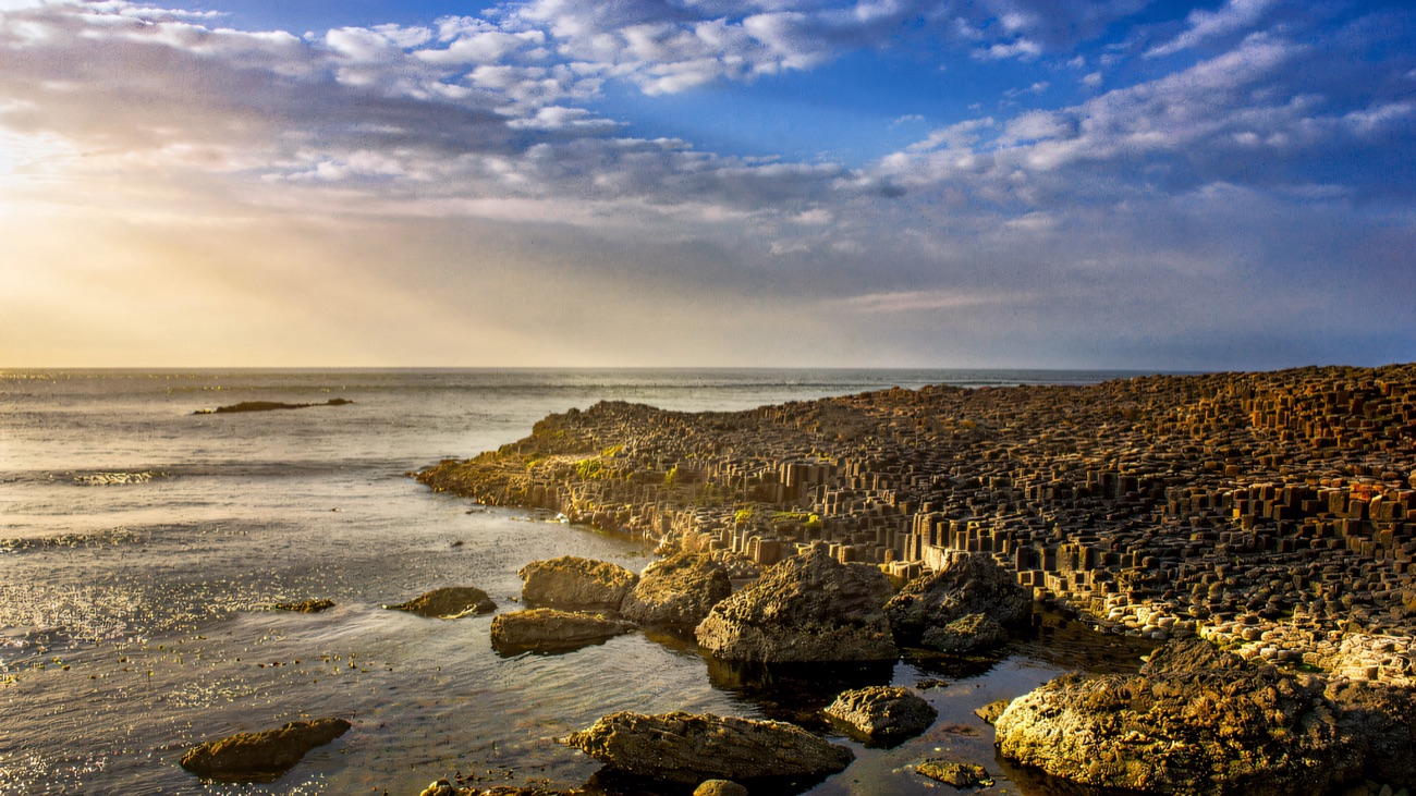 The Giant's Causeway basalt columns meeting the sea under a blue sky