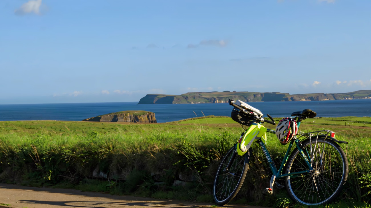 A touring bike pauses on the route with the Antrim headlands stretching out beyond