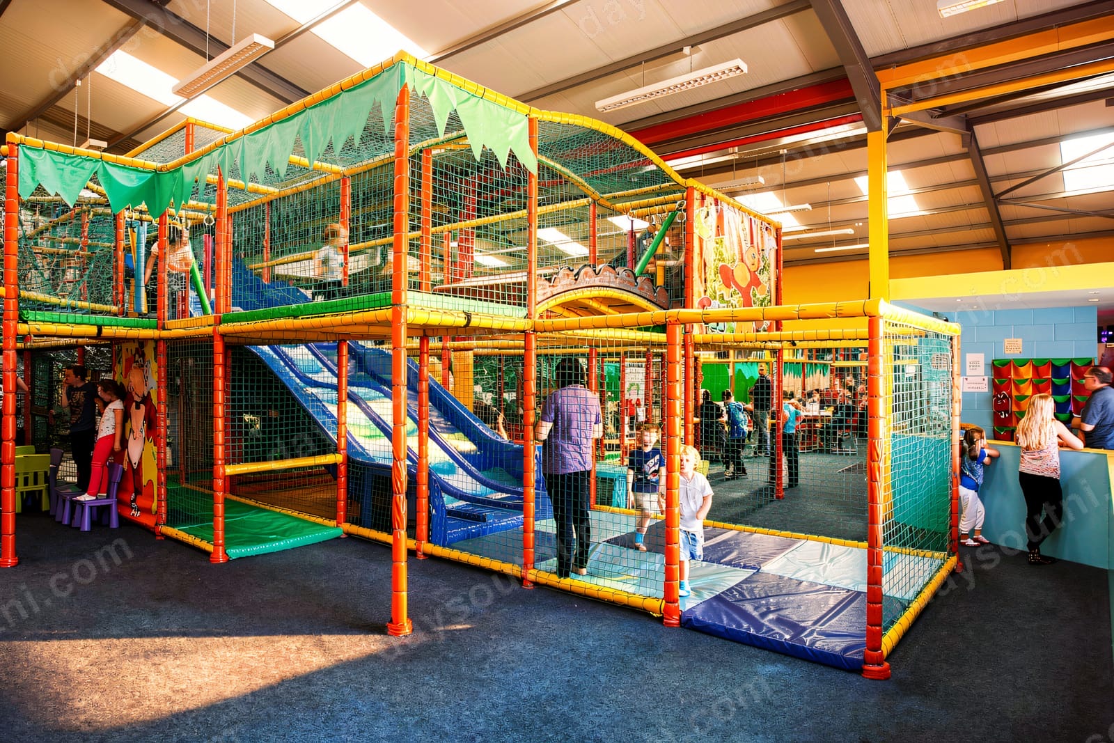 The colourful multi-level soft play frame inside Cheeky Chimps Coleraine, with red and yellow poles, green netting and slides