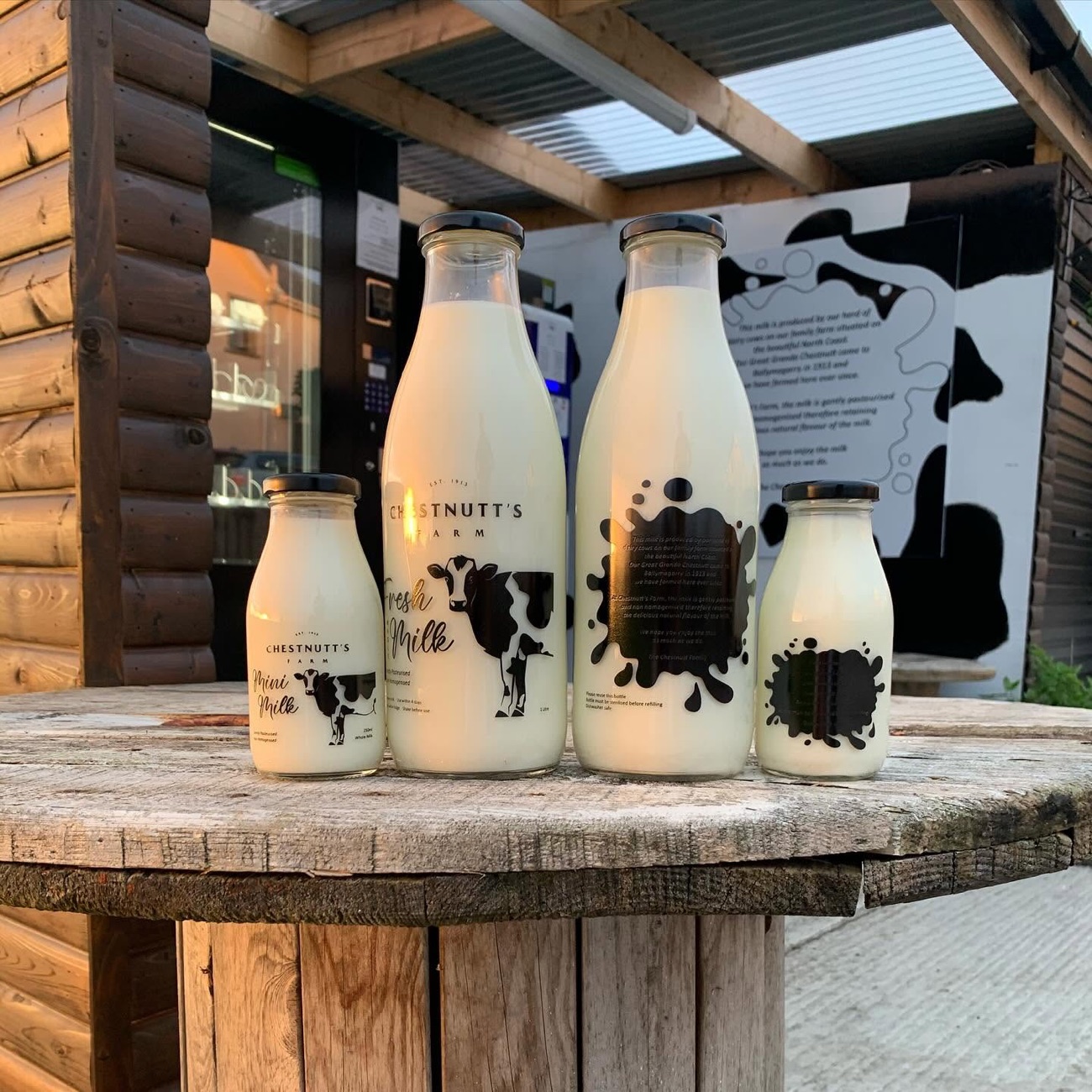 Chestnutt's Farm's own glass bottles of fresh milk lined up on a cable-reel table outside the hut