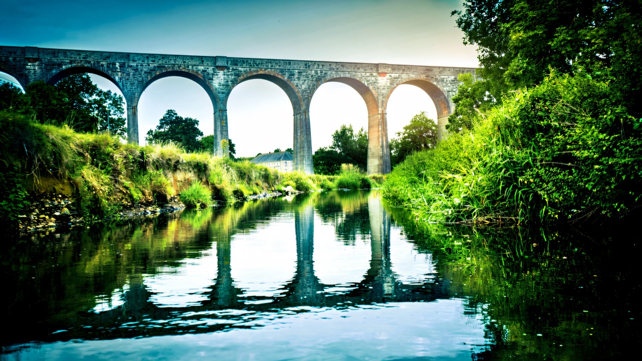 The arches mirrored in the still river, viewed from low on the water.