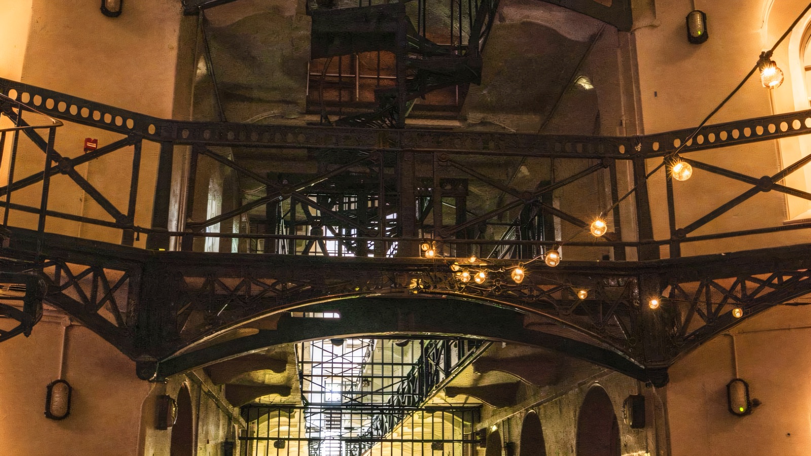 The great Victorian C-wing atrium at Crumlin Road Gaol, with tiered iron walkways and hanging lamps