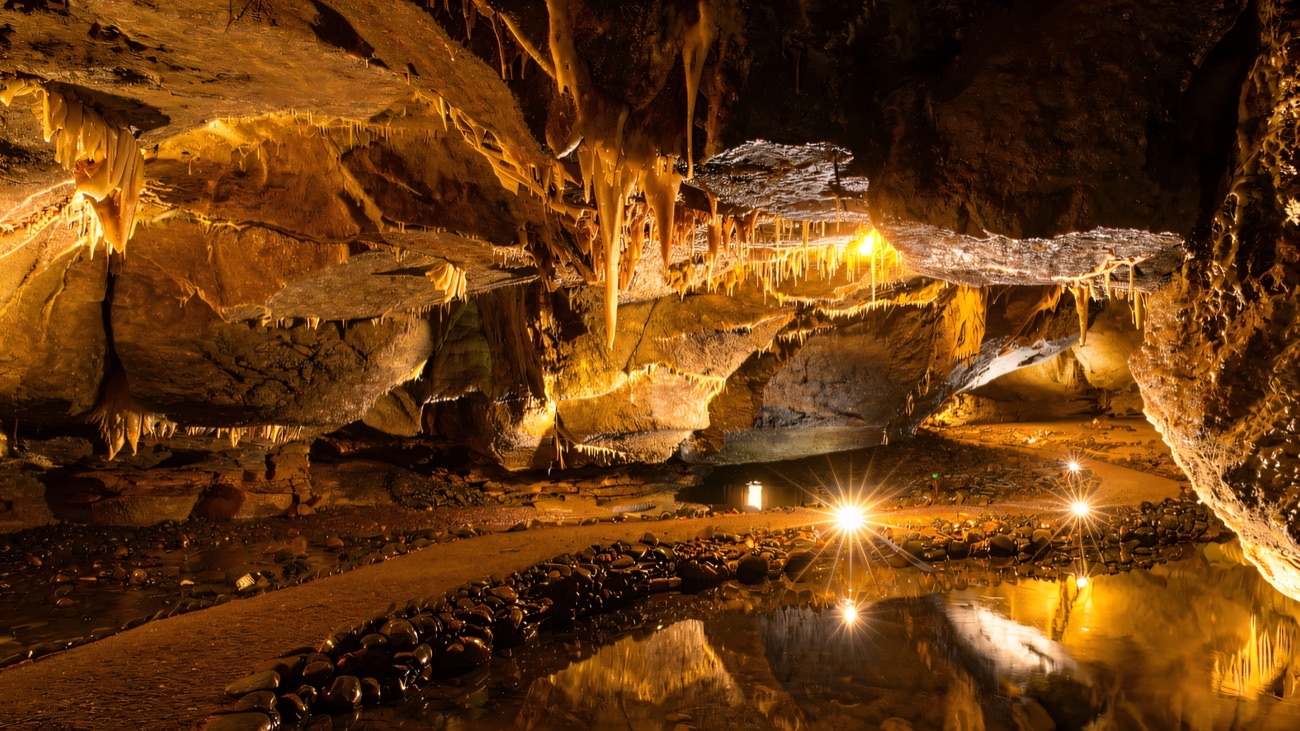 Floodlit stalactites and a mirror-still underground pool inside the Marble Arch Caves