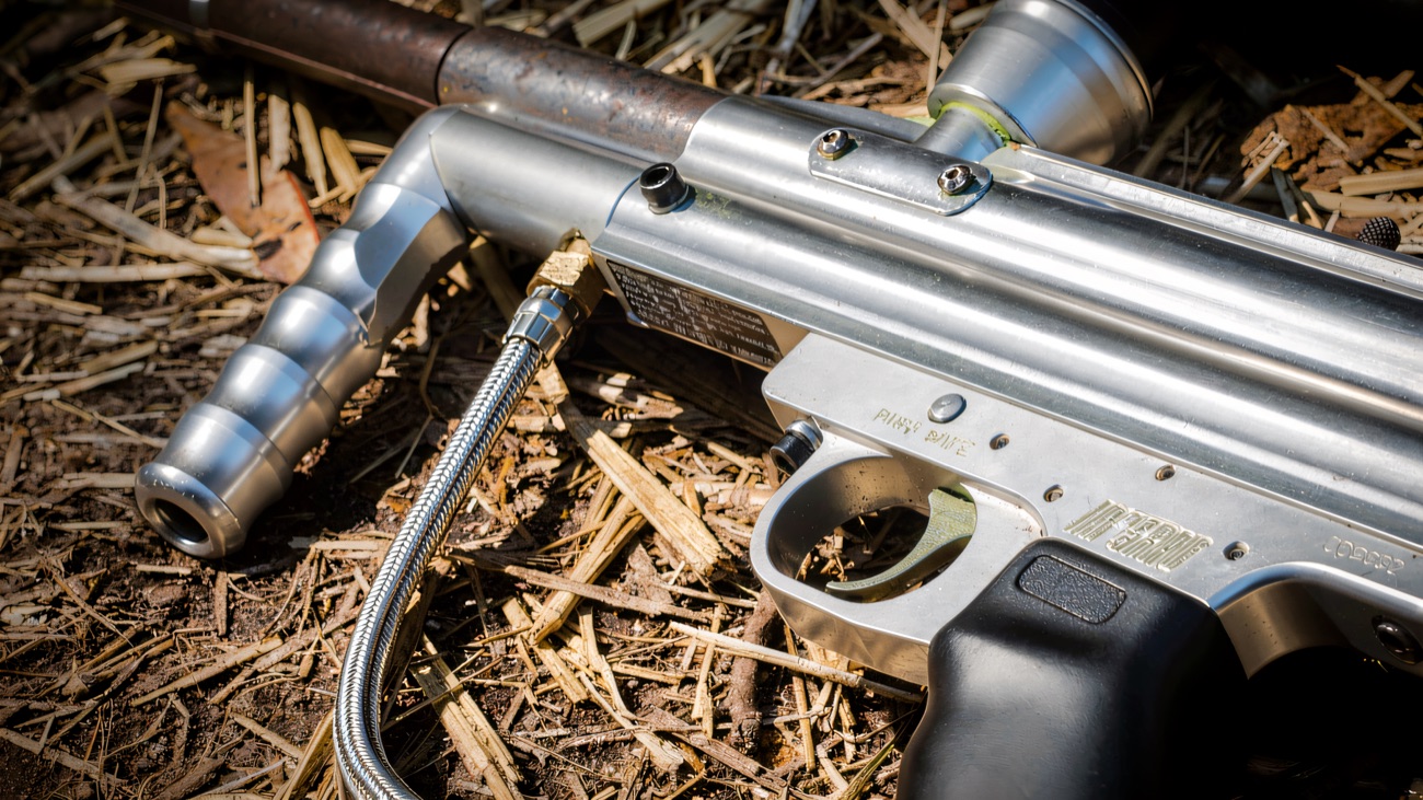 Close-up of a paintball marker resting on straw between games