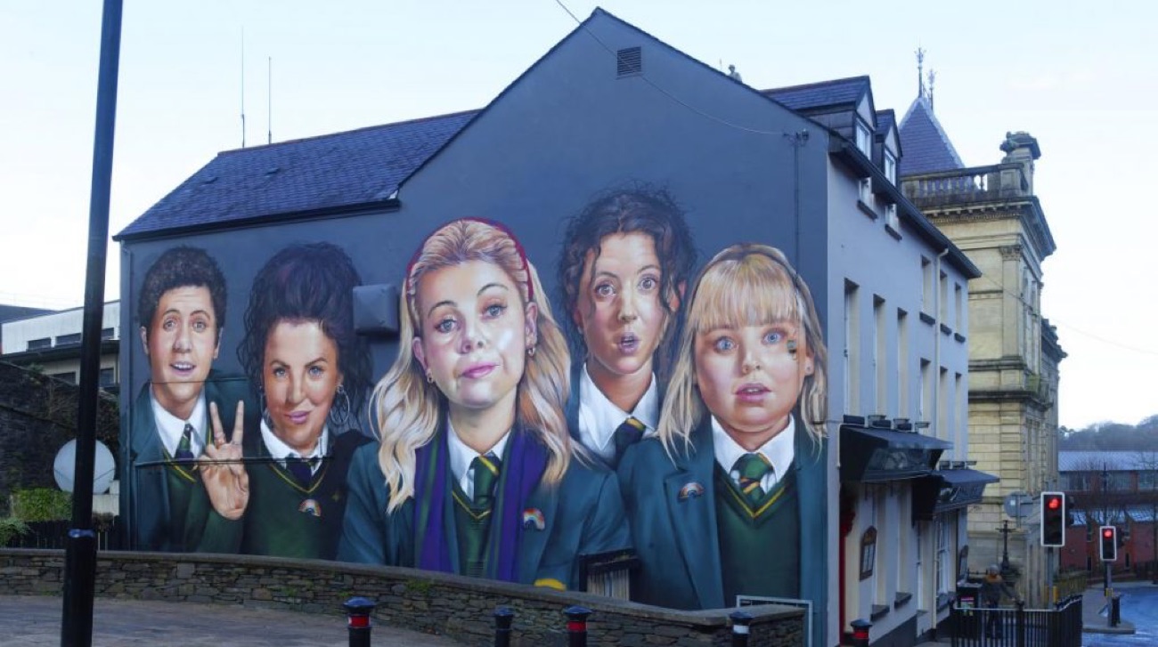 Wide street view of the mural on the pub gable, with the ornate city-centre buildings alongside