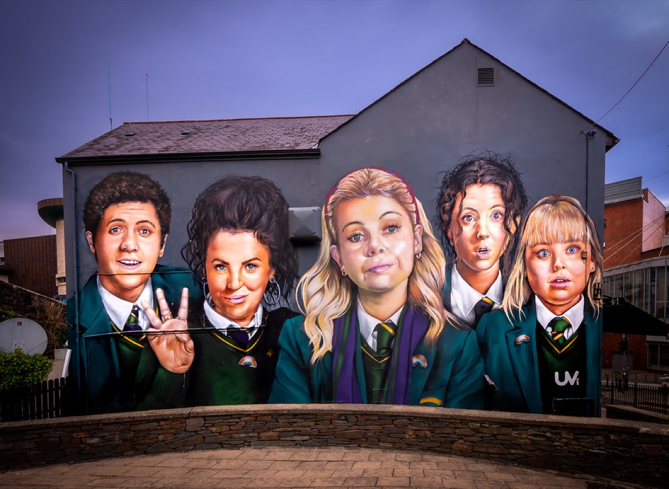 The mural lit at dusk, the five characters glowing against a deep blue evening sky