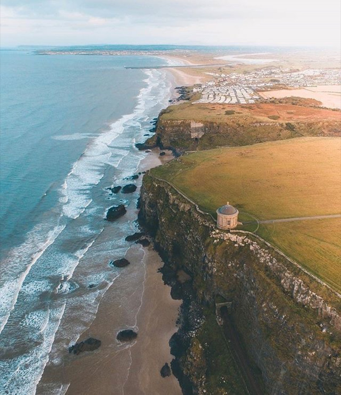Aerial view of Downhill Beach with Mussenden Temple on the cliff edge above the strand