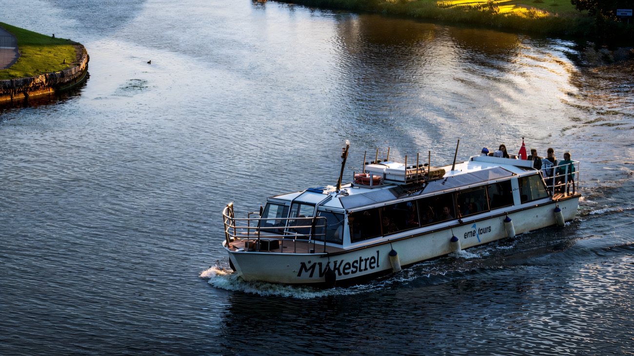 The boat under way along the river with passengers on the open deck