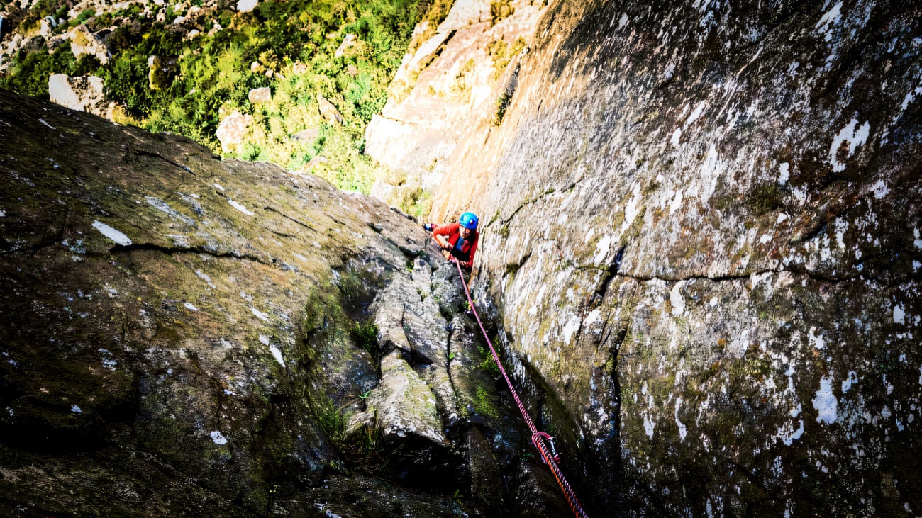 A roped climber high in a corner of the grey dolerite crag