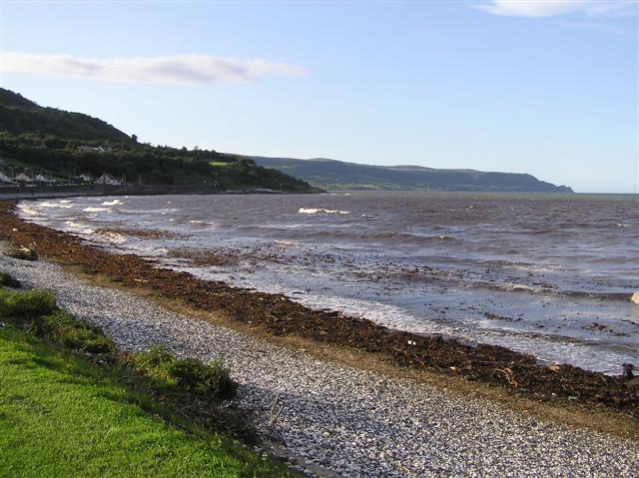The pebble and shingle beach at Glenarm with the green promenade beside it and Garron Point in the distance