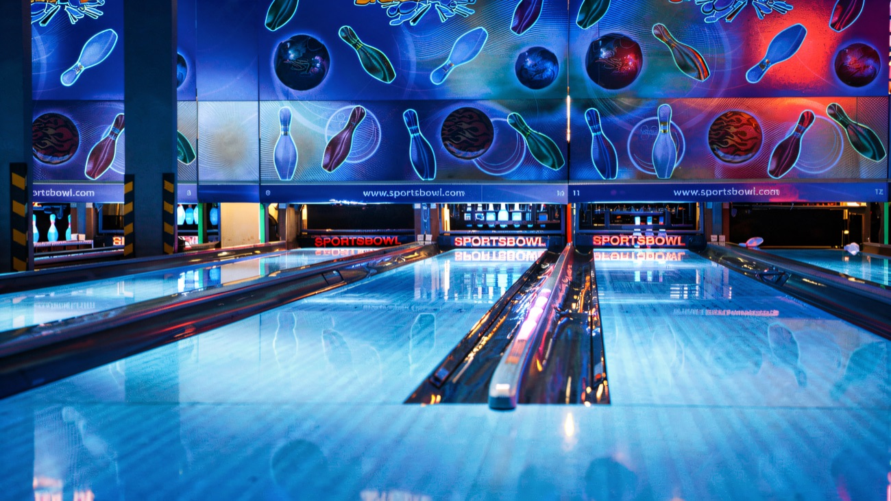 Sportsbowl lanes glowing blue under the neon pin murals