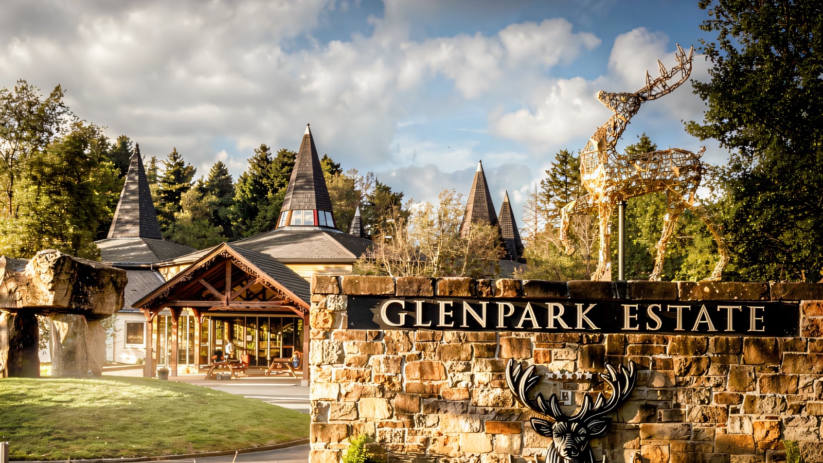 The stone Glenpark Estate entrance sign with a golden stag sculpture and the turreted estate buildings behind, set against a Sperrin backdrop
