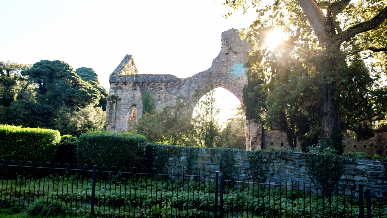 The west gable and its great arch, with sun flaring through the trees beyond.