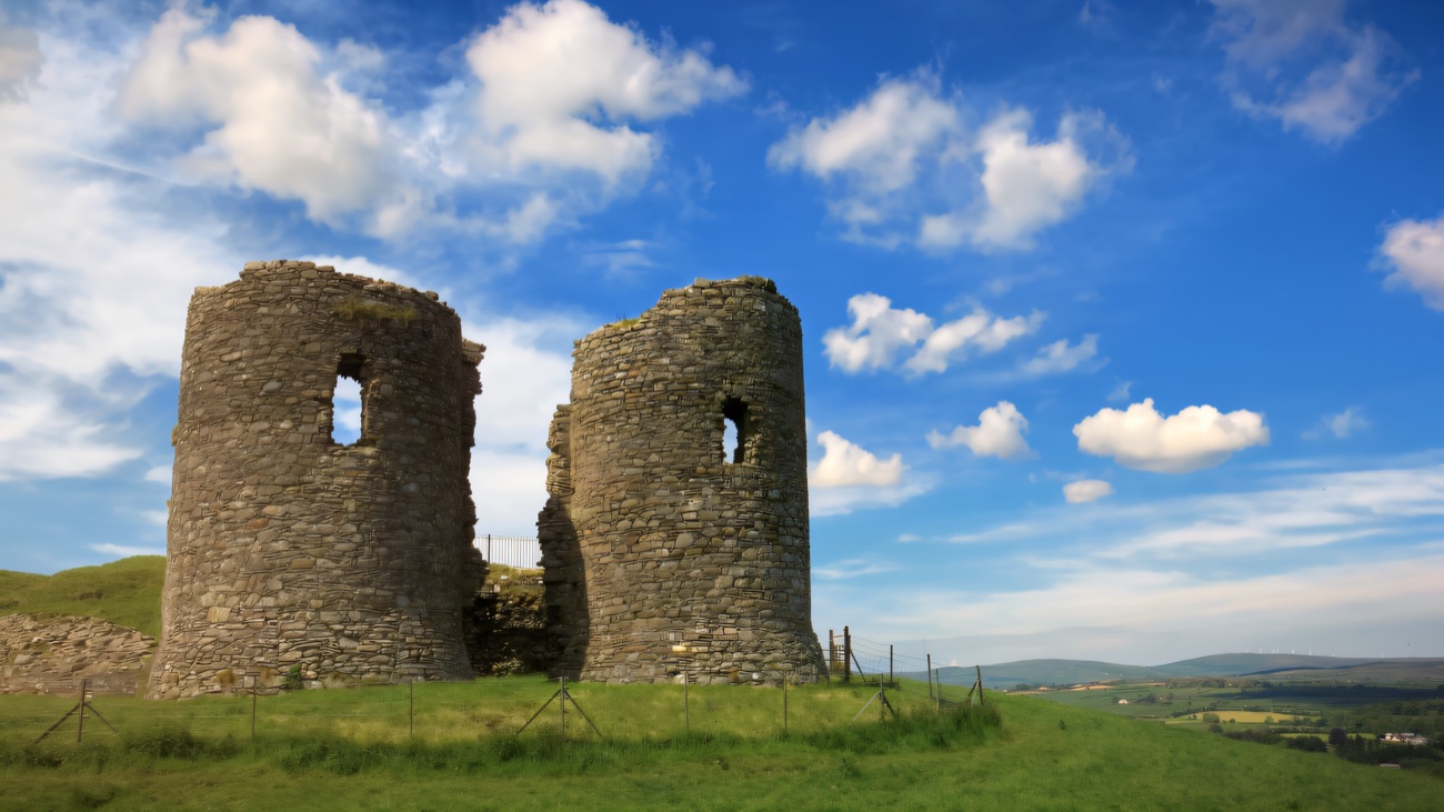 The distinctive drum towers of the gatehouse against a bright cloud-flecked sky