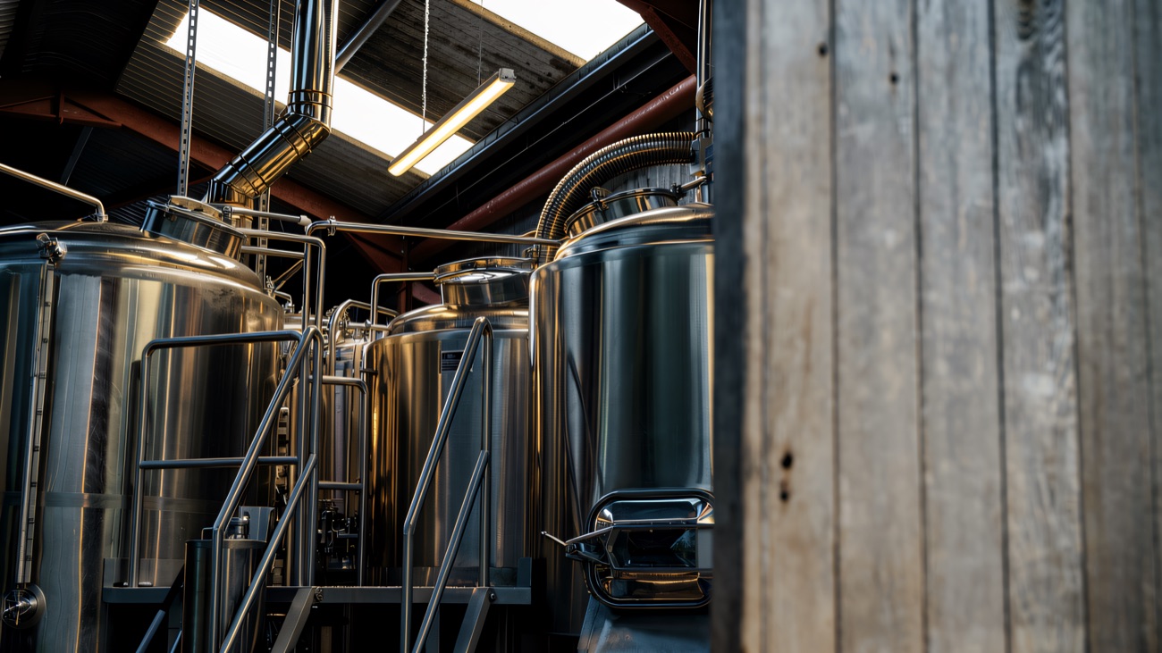 Rows of stainless steel brewing tanks under the pitched roof of the brewhouse