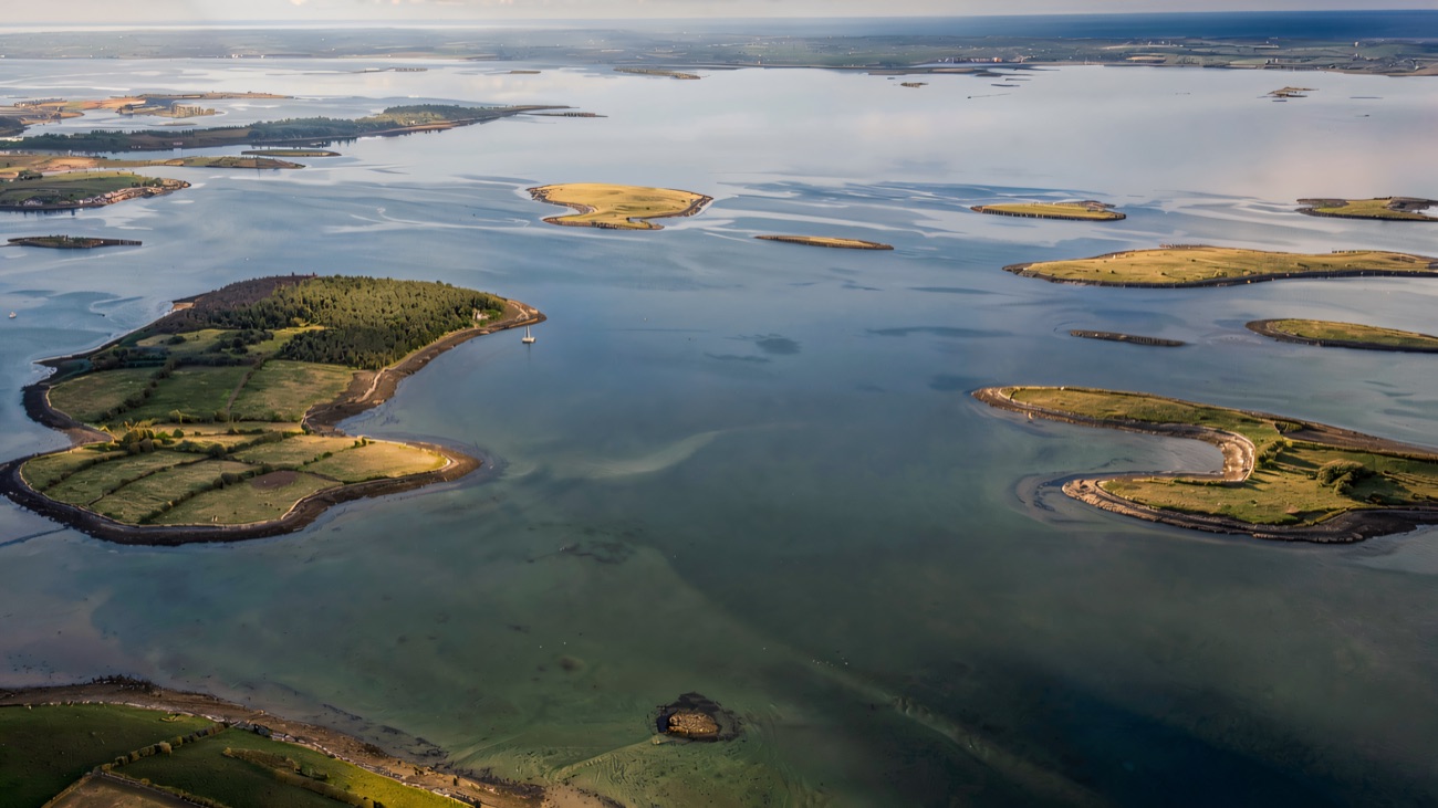 An aerial view over a lough dotted with small green islands and drumlins