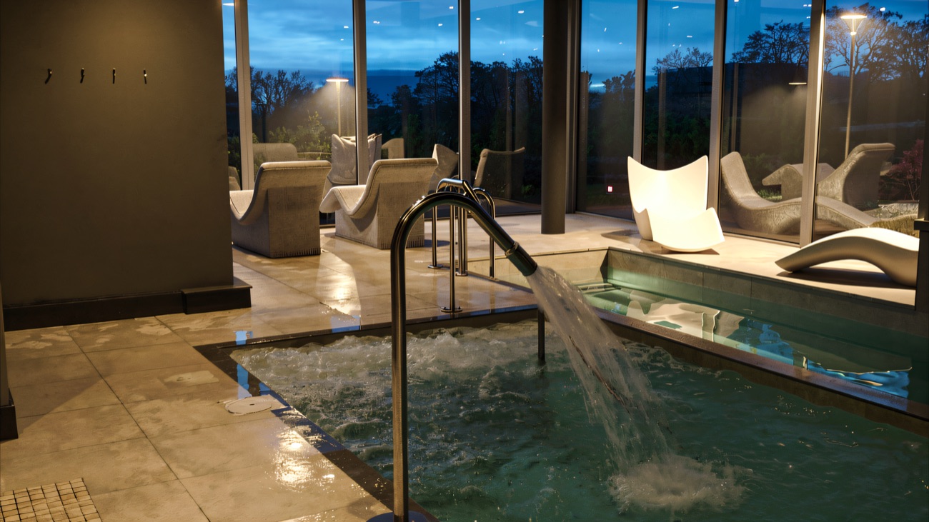 The same pool room at dusk, the sky turning blue beyond the glass wall.