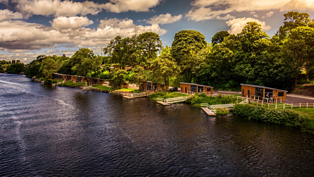 A row of timber self-catering chalets set among trees right on the lakeshore at Killyhevlin