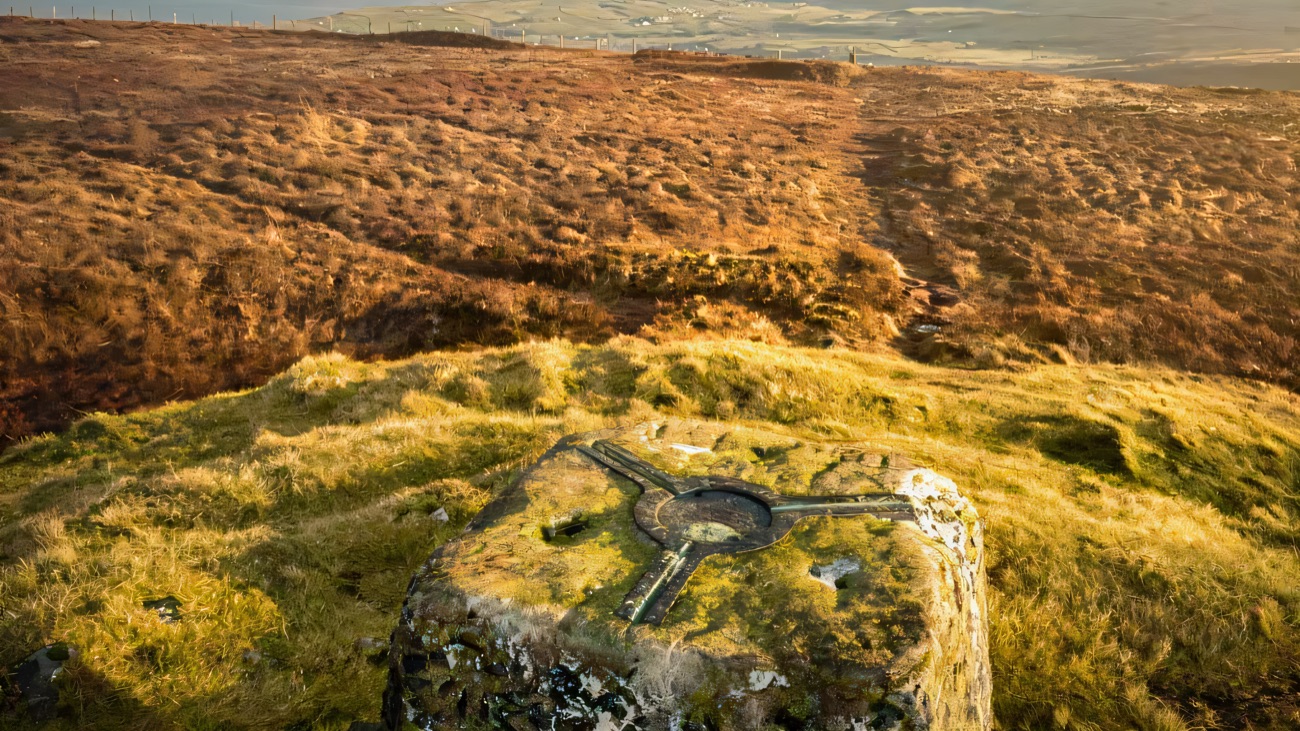 The summit trig point on golden moorland, Fair Head on the horizon