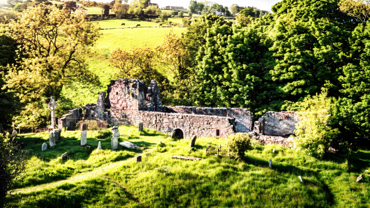 The old church and graveyard tucked into a green glen fold above the sea.