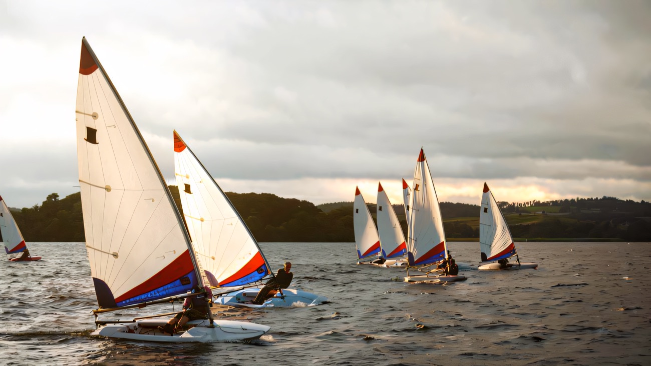 A fleet of dinghies leaning through a Lough Erne regatta